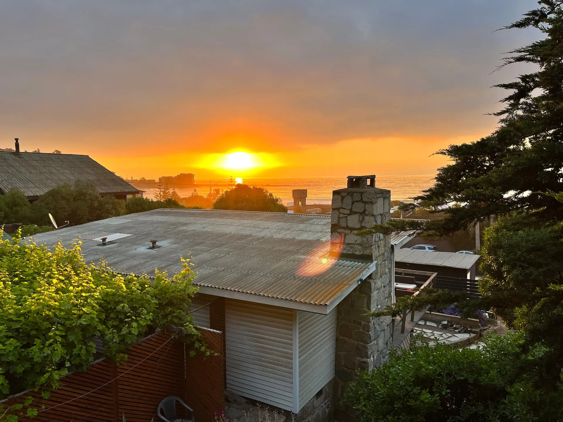 Atardecer sobre la casa principal de Lodge Maitencillo, con su chimenea de piedra y el mar al fondo