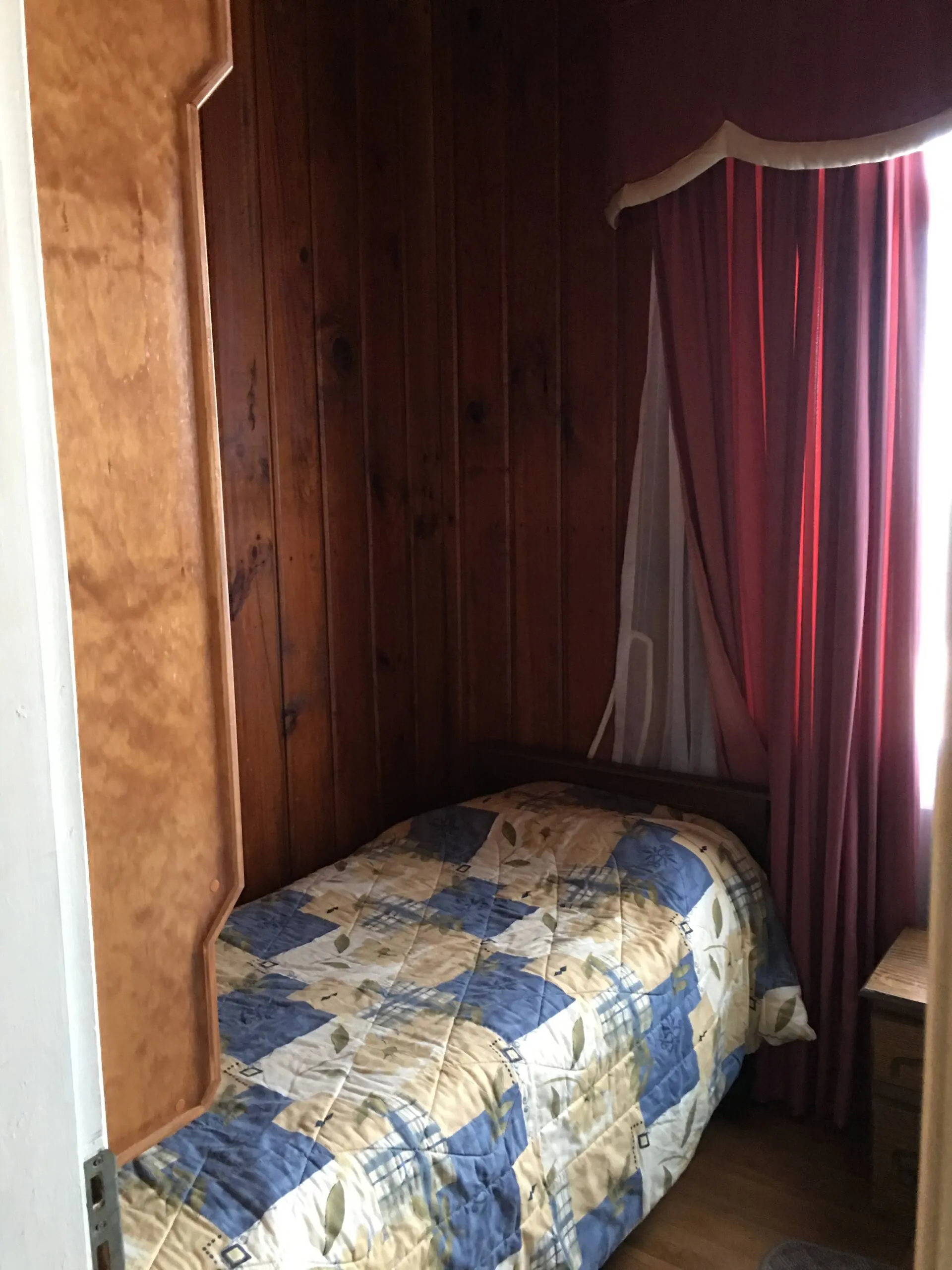 Dormitorio de la casa principal con cama individual y muros de madera