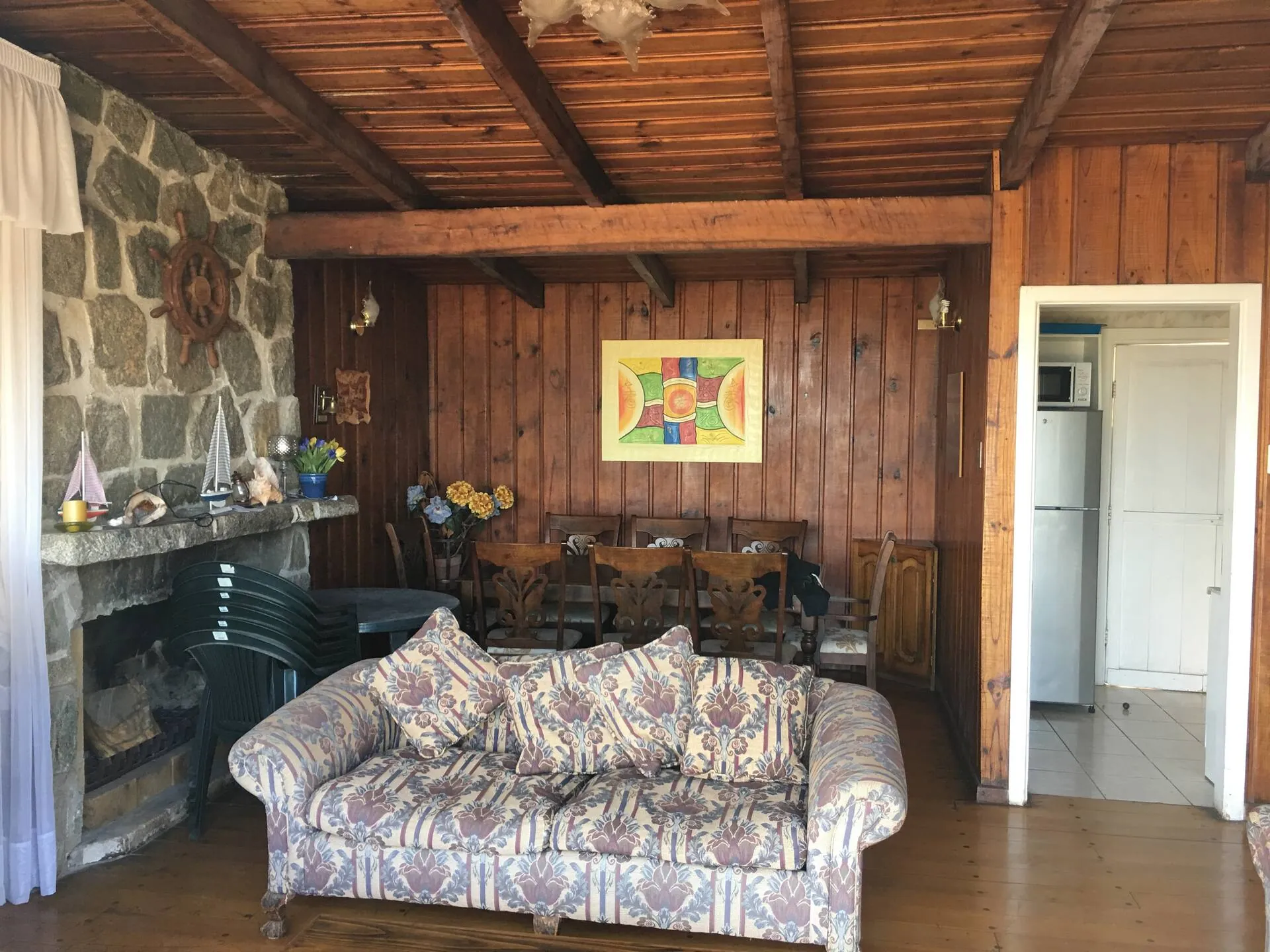 Living de la casa principal con chimenea de piedra y revestimiento de madera