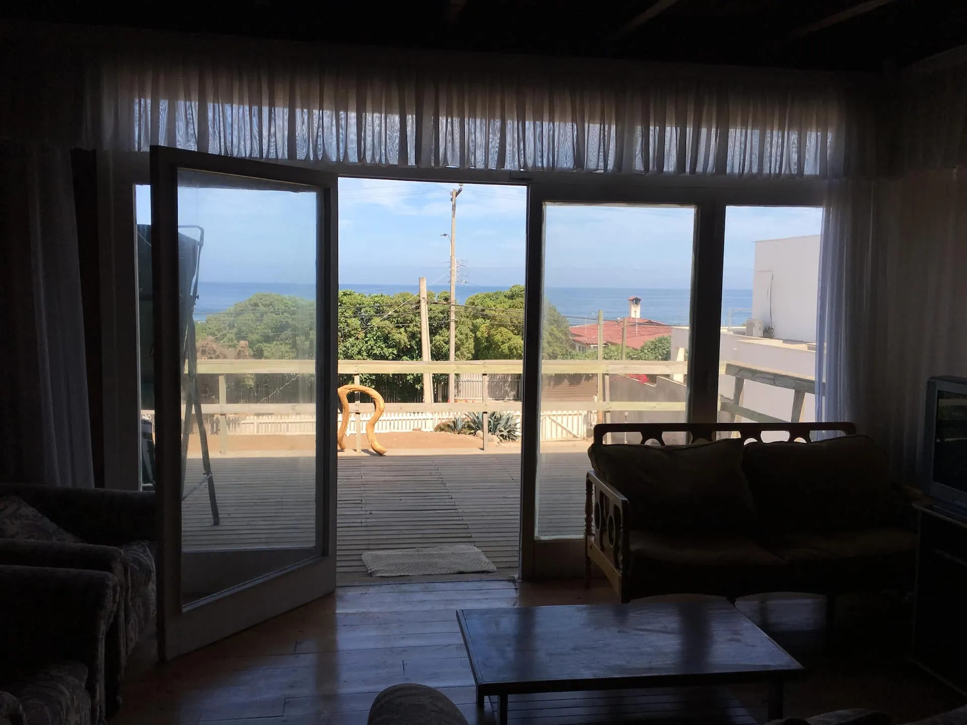 Living de la casa principal abierto a la terraza con vista al mar