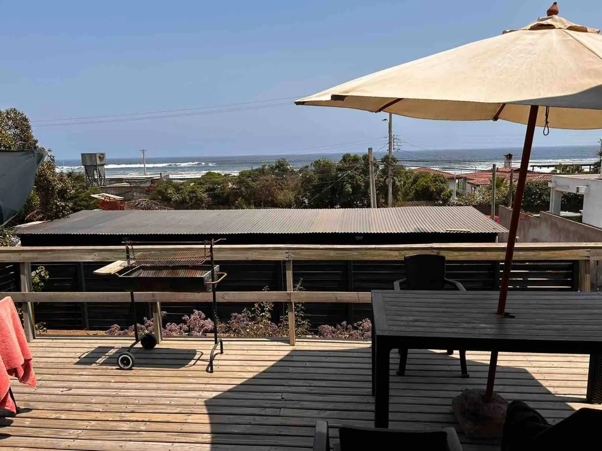 Terraza de la casa principal con parrilla, mesa y vista al mar