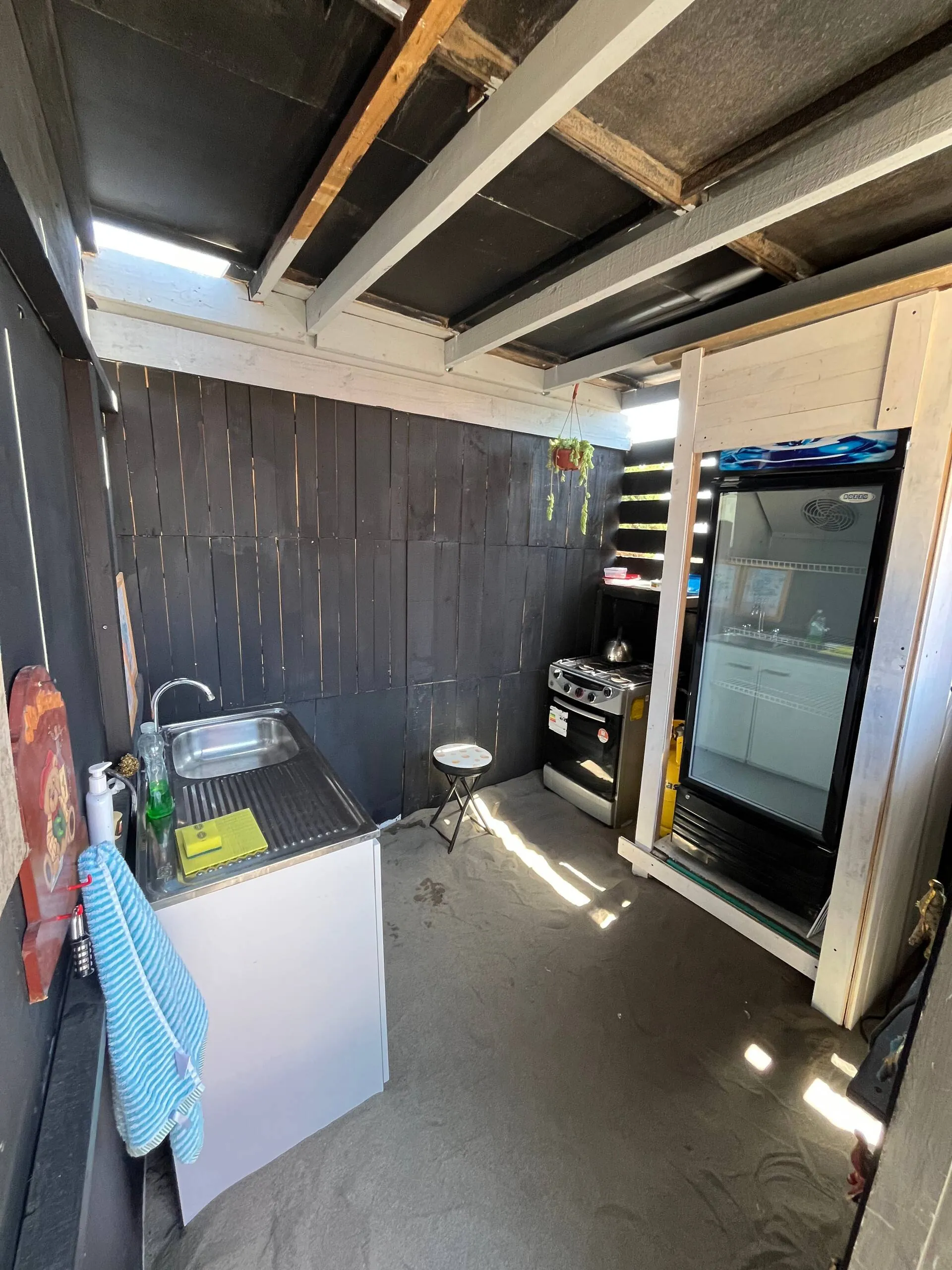 Cocina exterior de la tiny house con lavaplatos, cocina y refrigerador