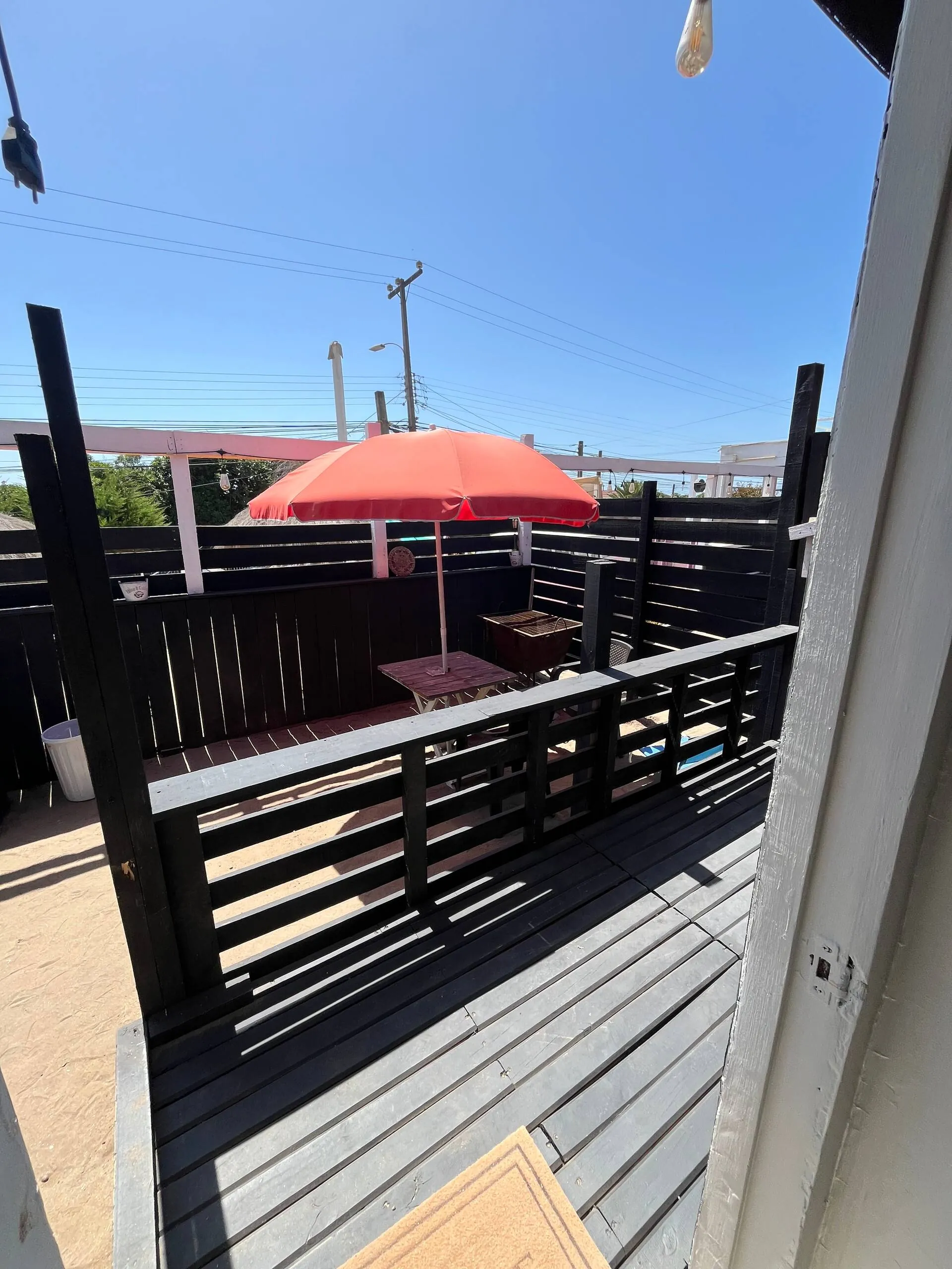 Deck de madera de la tiny house con quitasol y parrilla