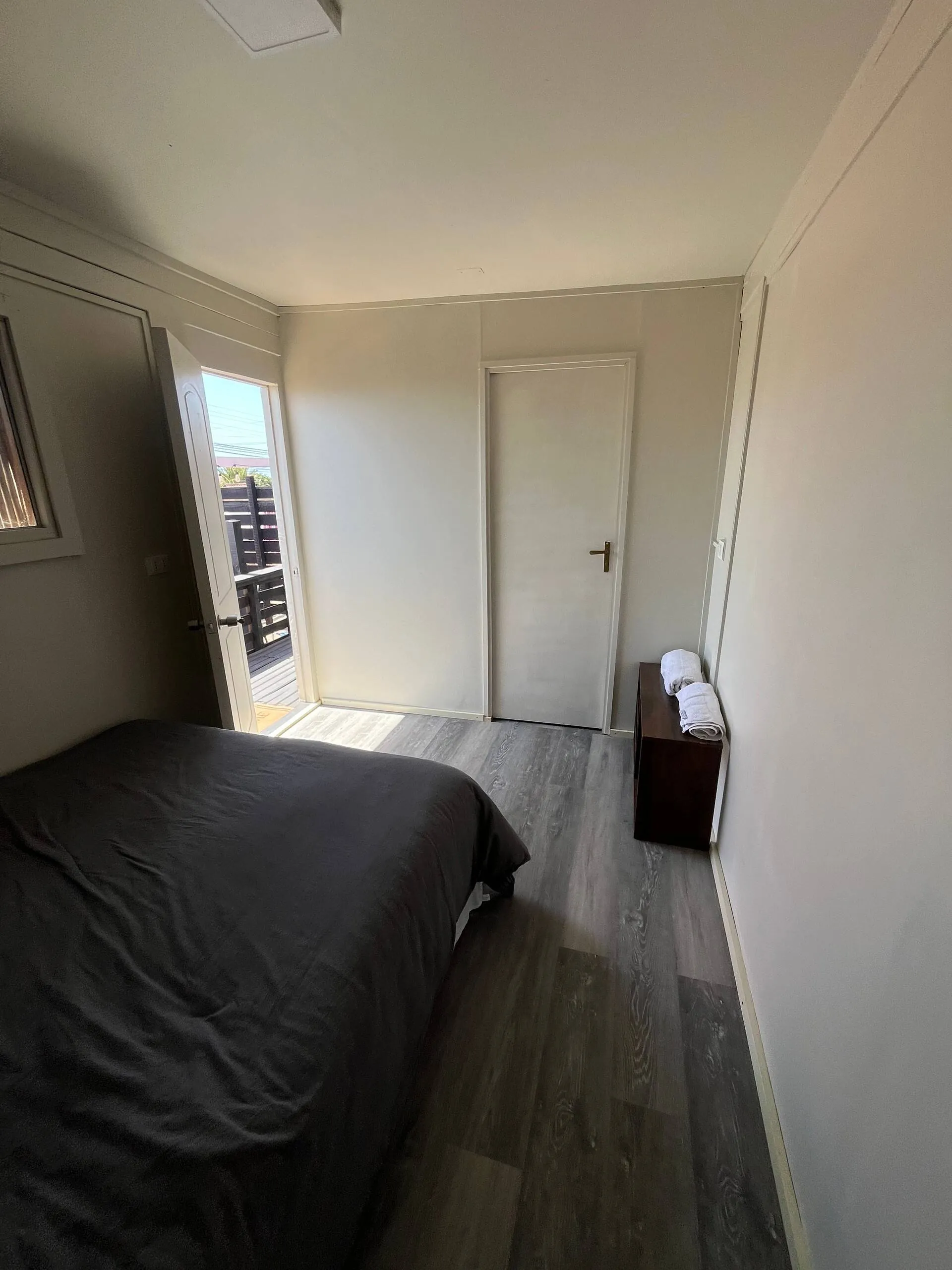 Dormitorio de la tiny house con cama de dos plazas y puerta a la terraza