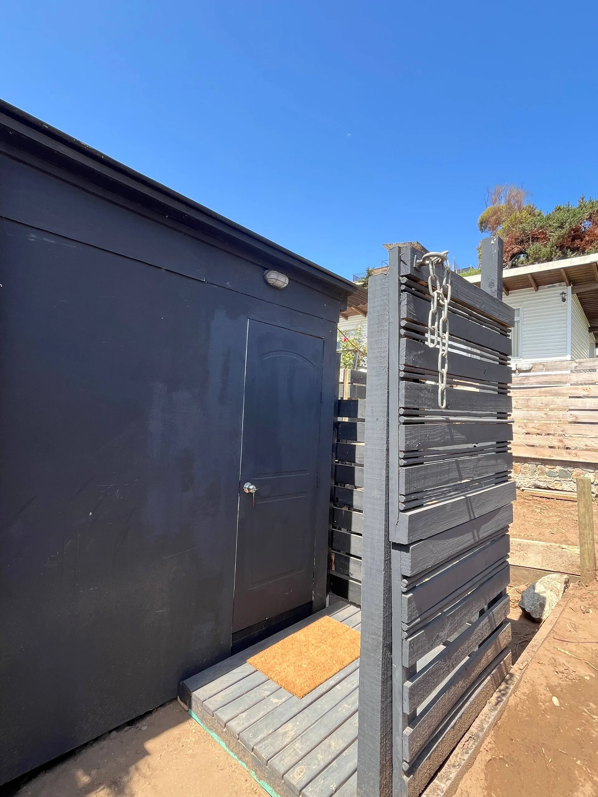 Fachada negra de la tiny house con su terraza de madera