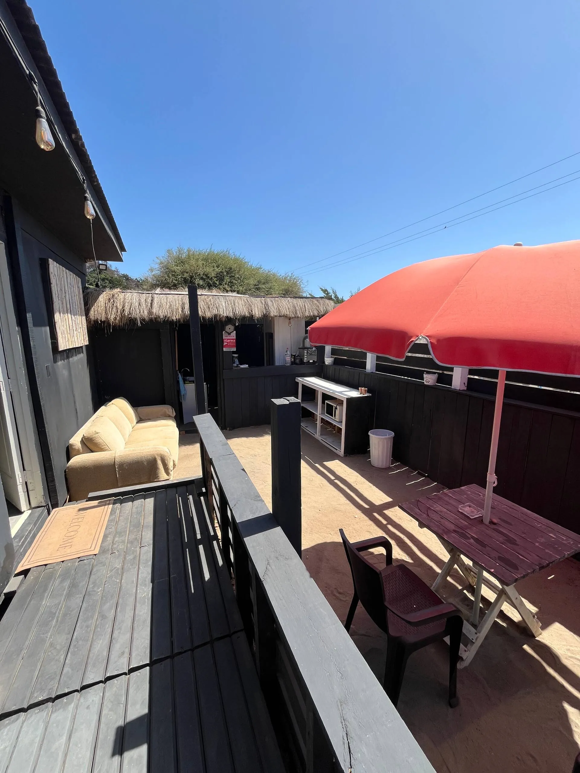 Terraza de la tiny house con quitasol, sofá y cocina exterior